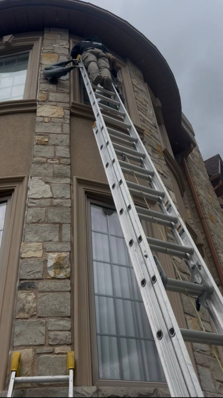 Extension ladder set against a curved stone facade during exterior work
