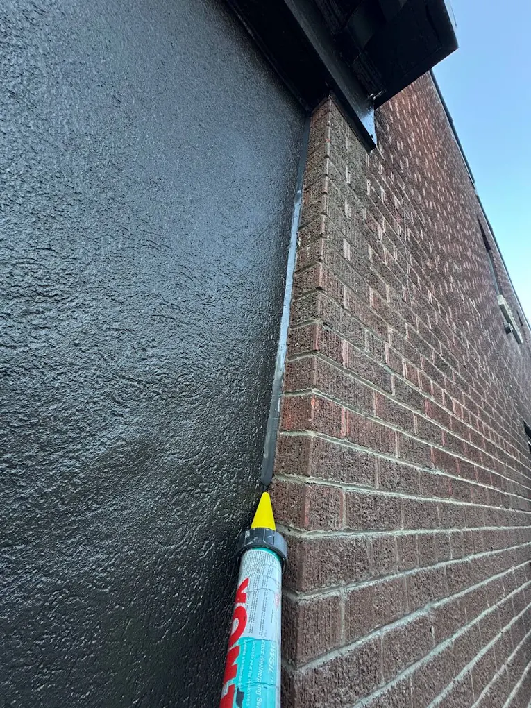 Sealant being applied to the joint between a stucco wall and a brick wall