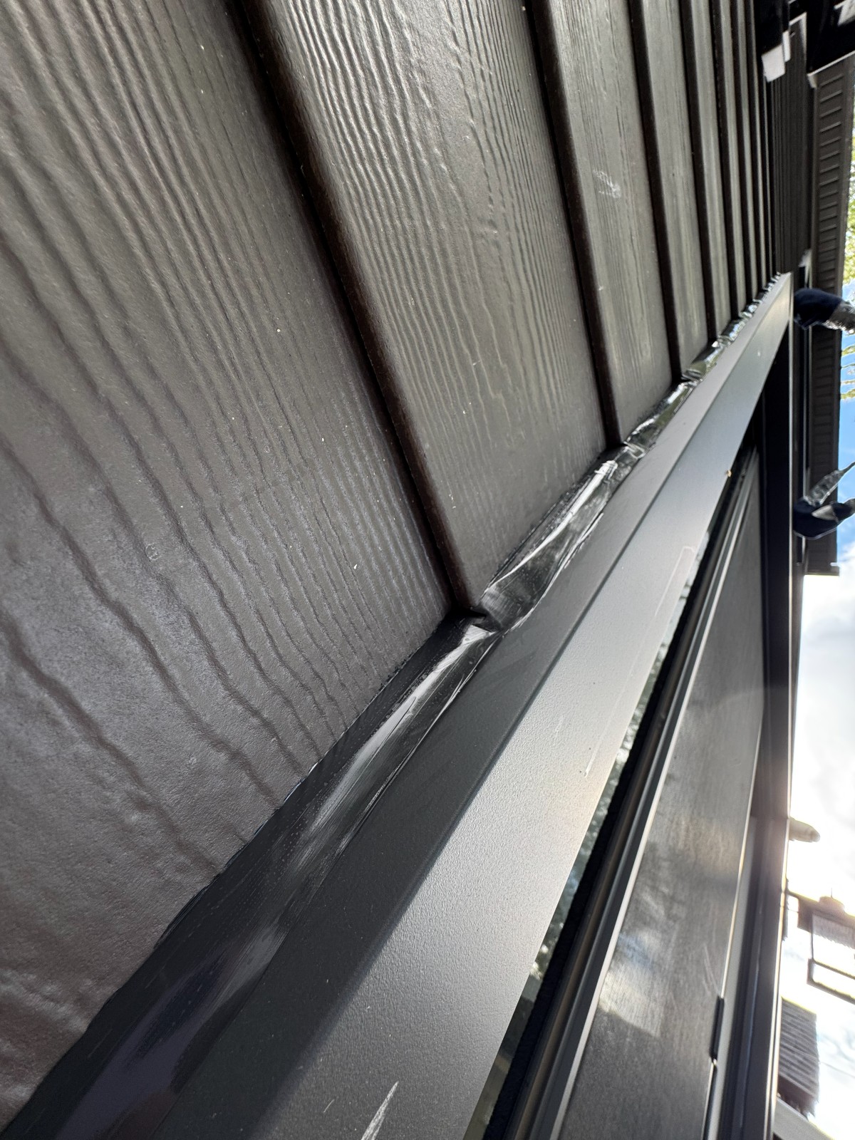 New sealant bead along an exterior siding and trim joint