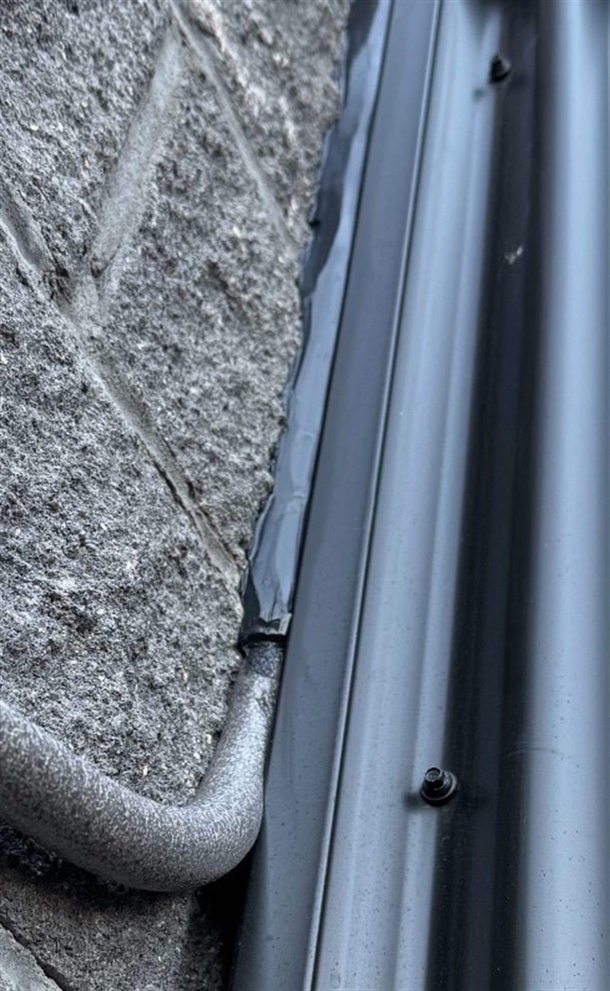 Sealed joint where a downspout meets a stone wall