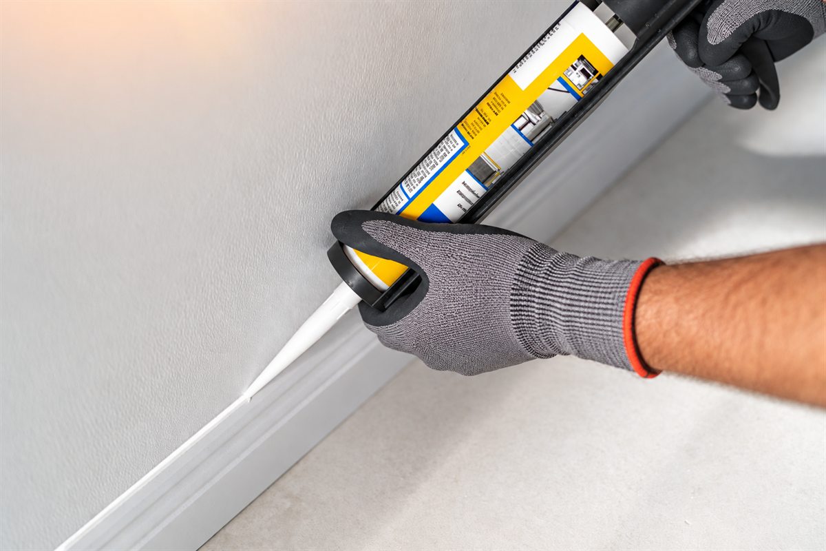 Interior caulking being applied along a baseboard