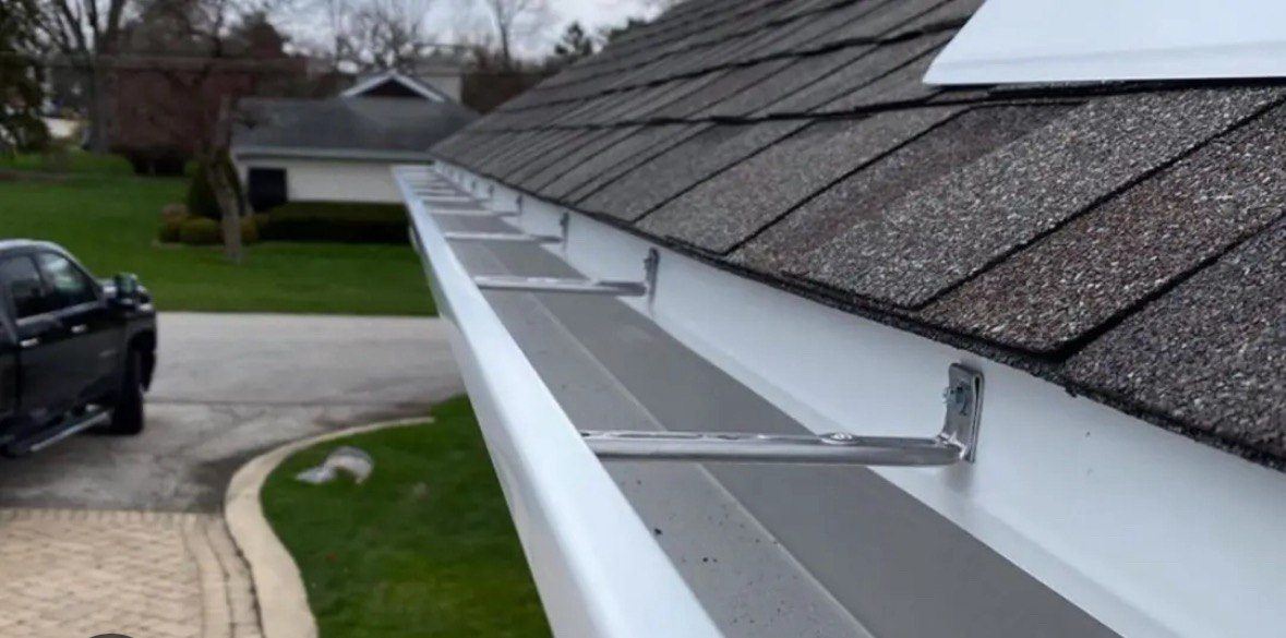 Gutter guard installed along a shingle roof edge