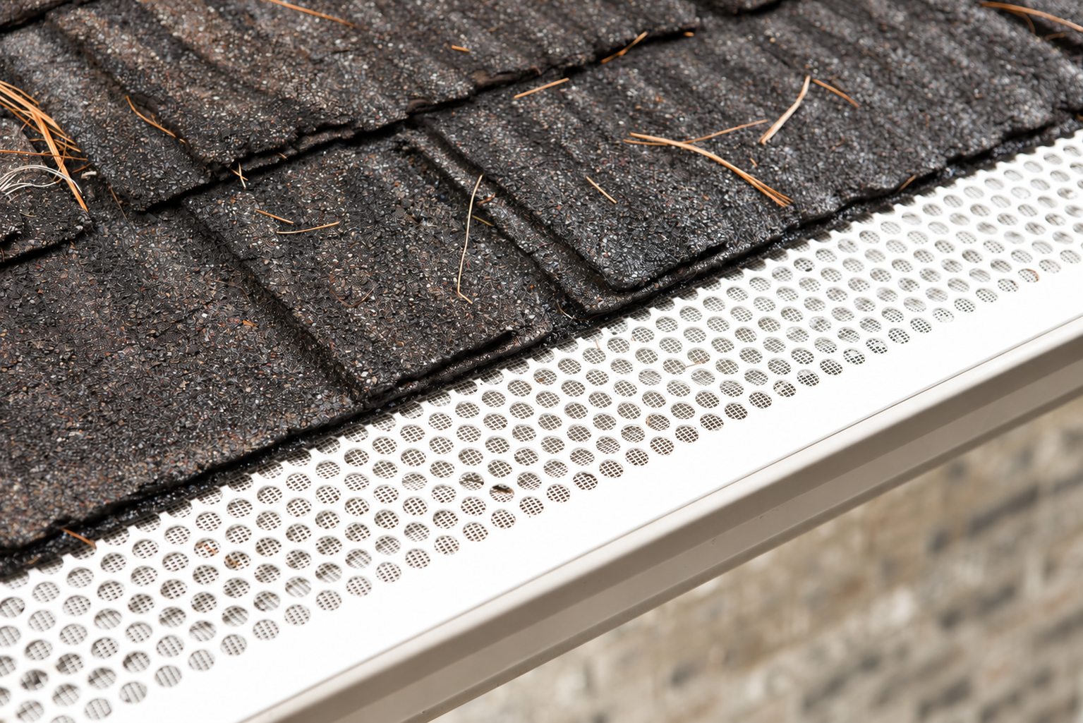 Aluminum gutter cover with stainless steel micro-mesh below a shingle roof edge