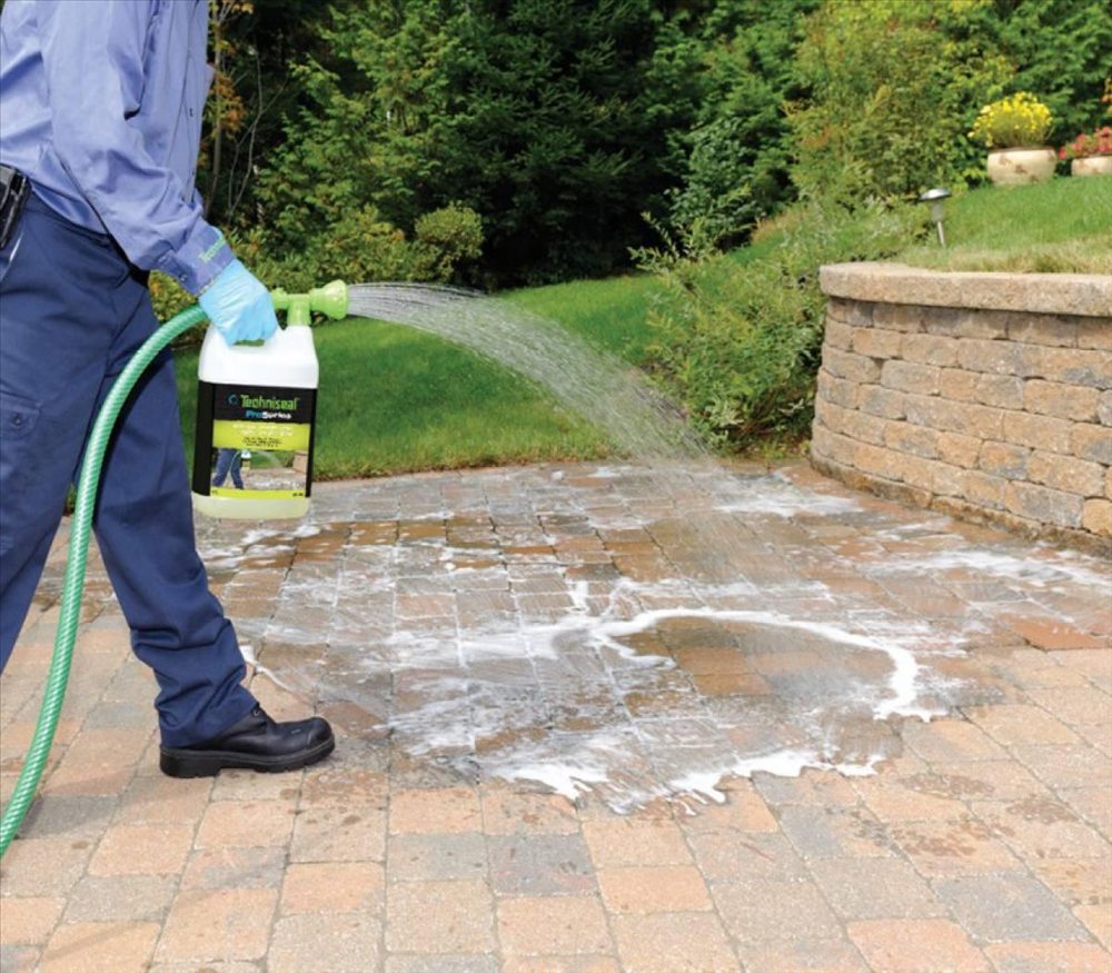 Cleaning solution being applied to paving stones from a hose-end sprayer
