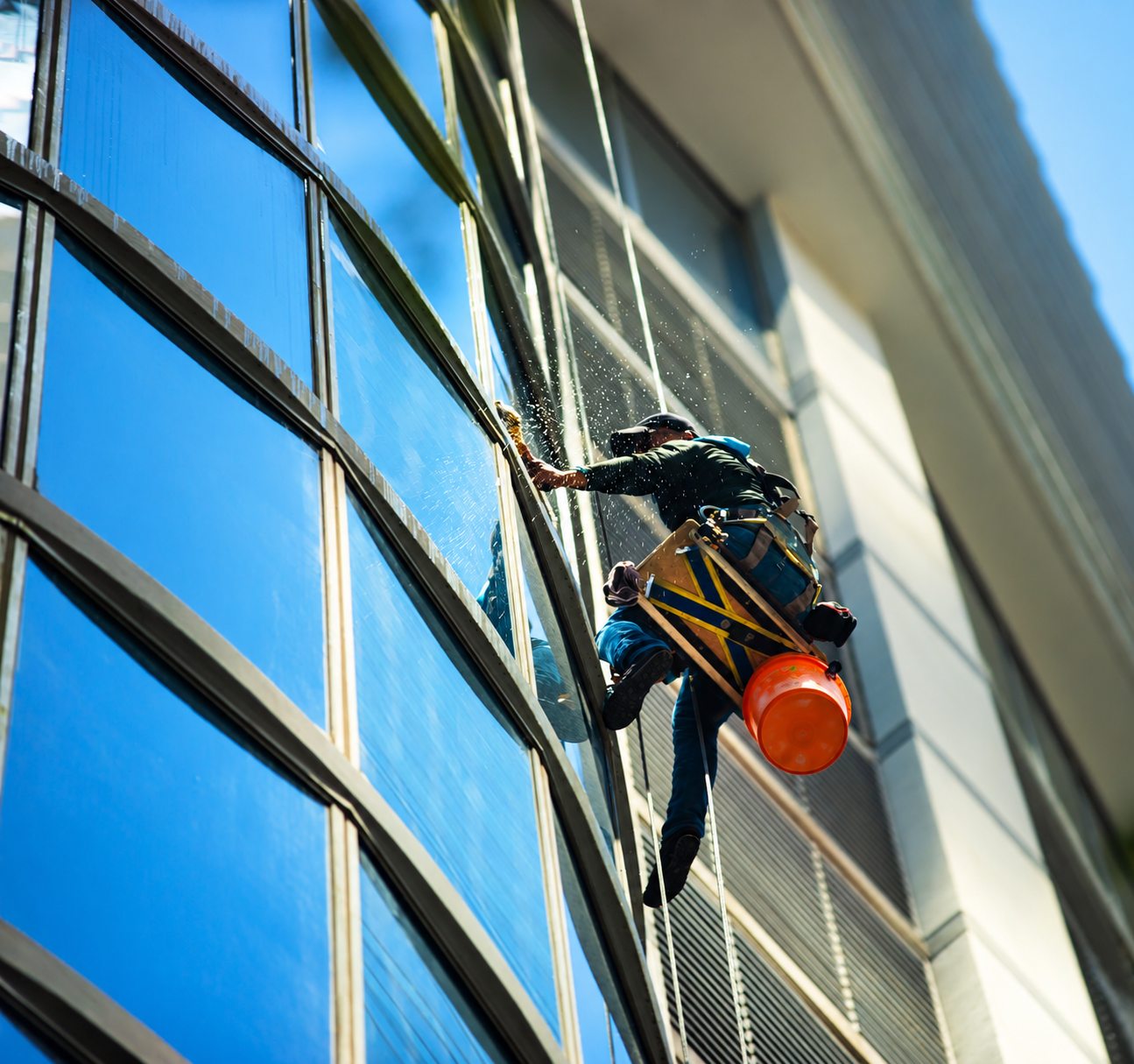 Rope-access window cleaner working on the glass of a tall building