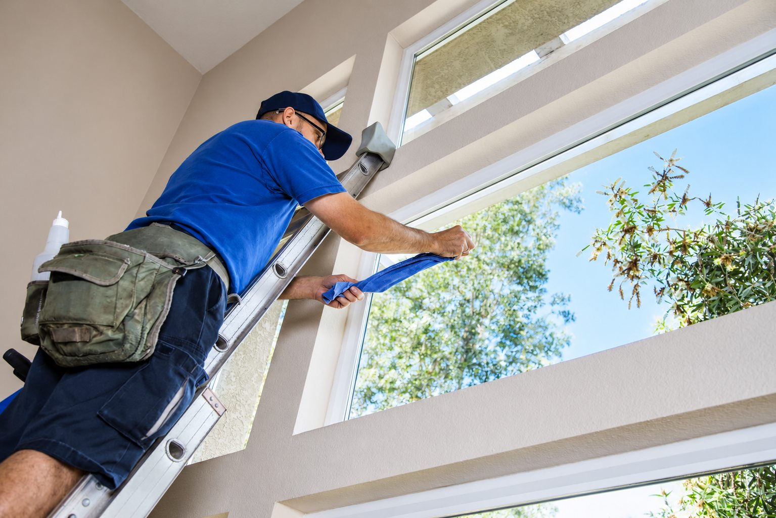 Window cleaner on a ladder wiping the inside of a high window