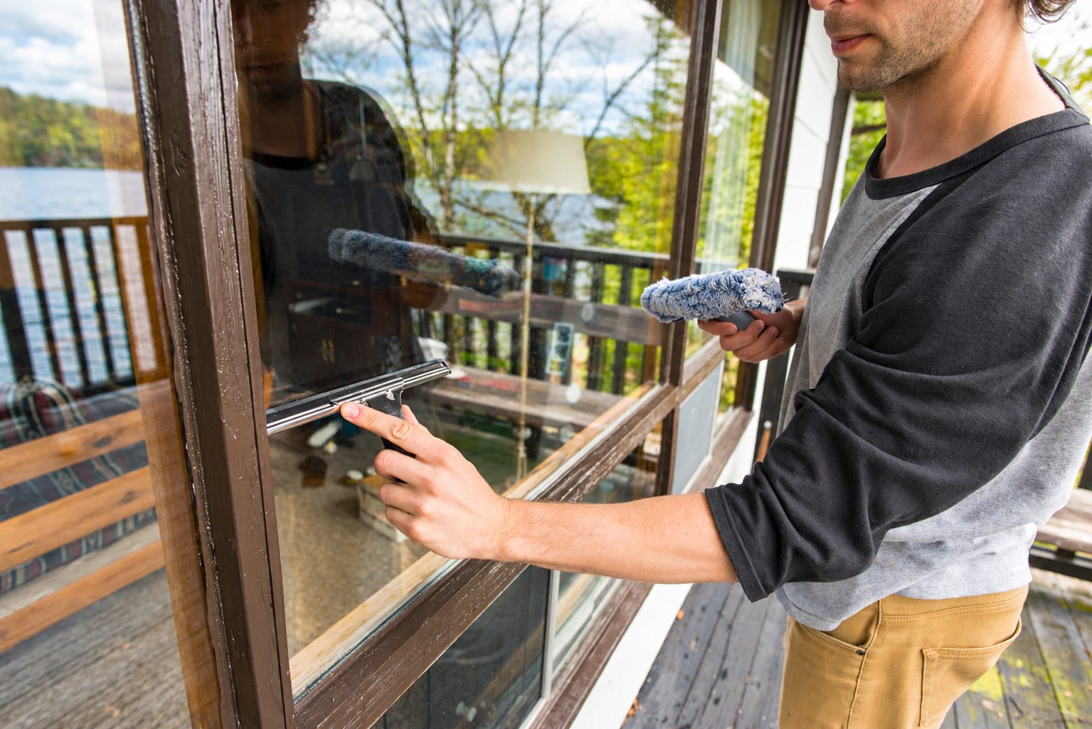 Cleaning a window by hand with a squeegee and washer